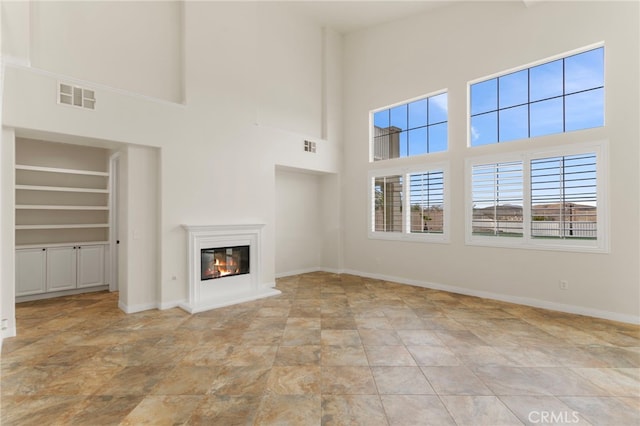 unfurnished living room with built in features and a high ceiling