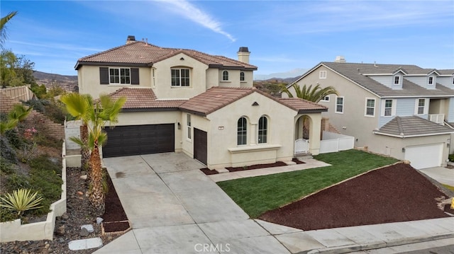 mediterranean / spanish house with a mountain view, a garage, and a front lawn