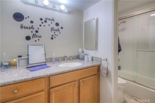 full bathroom featuring toilet, vanity, and shower / bath combination with glass door