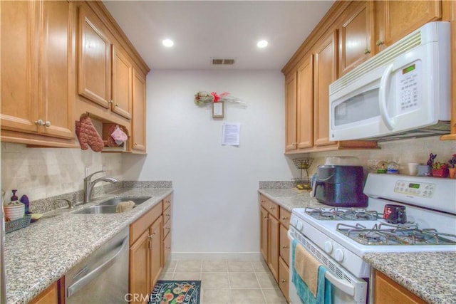 kitchen with light tile patterned flooring, sink, backsplash, light stone countertops, and white appliances