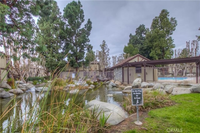 view of community featuring a pool and an outbuilding