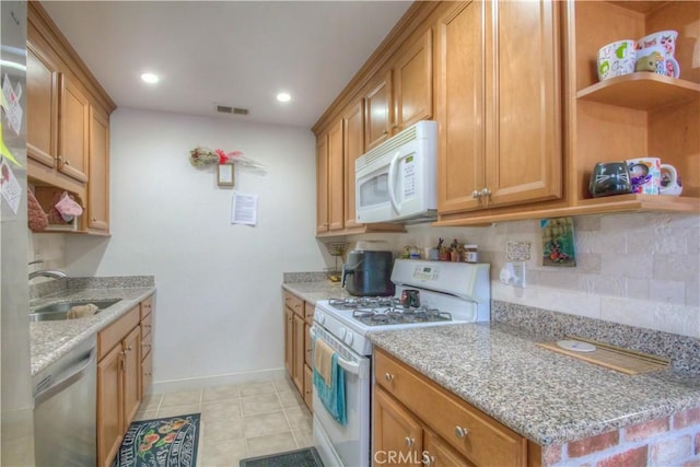 kitchen with light tile patterned flooring, sink, decorative backsplash, light stone counters, and white appliances