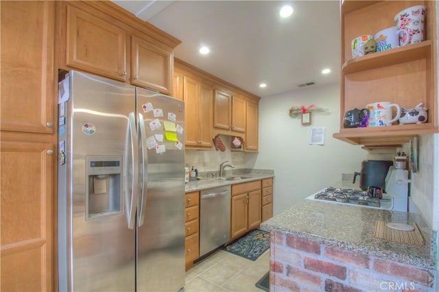 kitchen featuring light stone counters, sink, light tile patterned floors, and stainless steel appliances