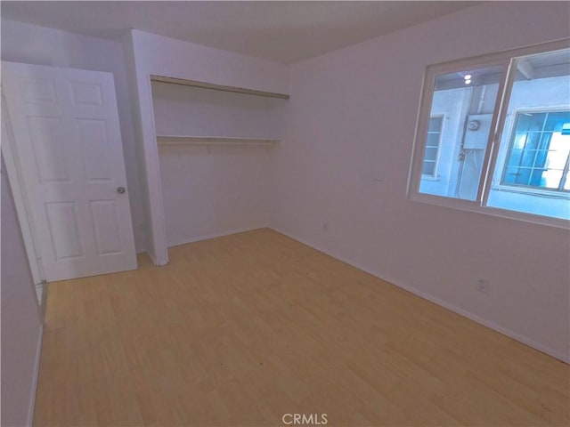 unfurnished bedroom with a closet and light wood-type flooring