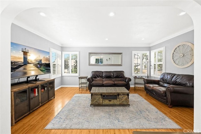 living room with ornamental molding, a healthy amount of sunlight, and light wood-type flooring