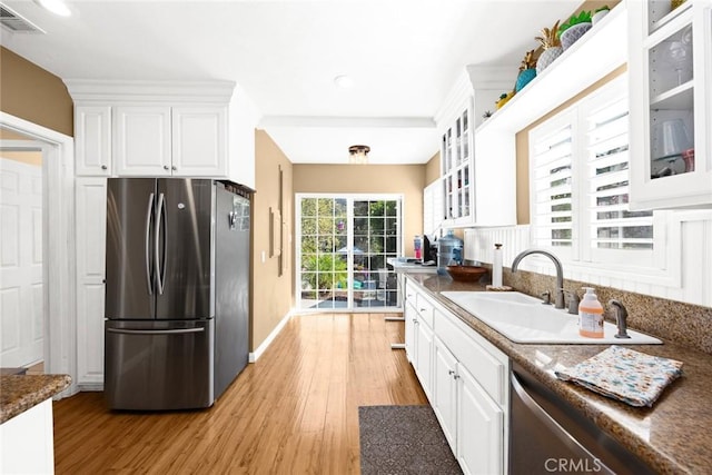 kitchen featuring white cabinetry, sink, dark stone countertops, stainless steel appliances, and light wood-type flooring