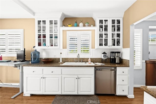 kitchen featuring hardwood / wood-style floors, sink, stainless steel dishwasher, and white cabinets