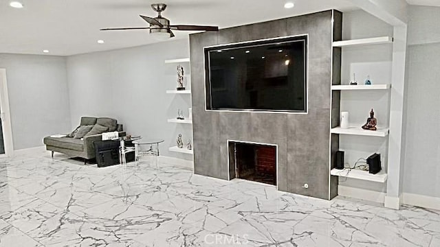 living room featuring ceiling fan, a large fireplace, and built in features