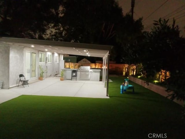 patio at night featuring area for grilling and a yard
