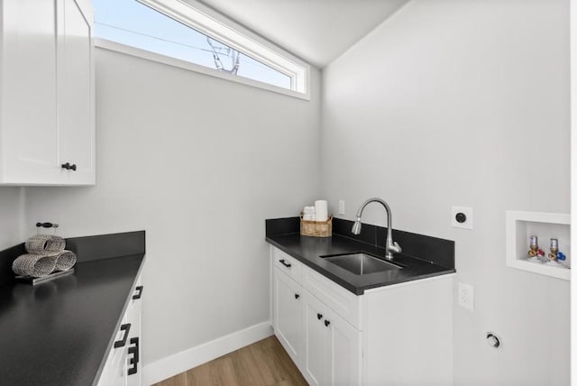 washroom featuring sink, light hardwood / wood-style flooring, electric dryer hookup, hookup for a washing machine, and cabinets