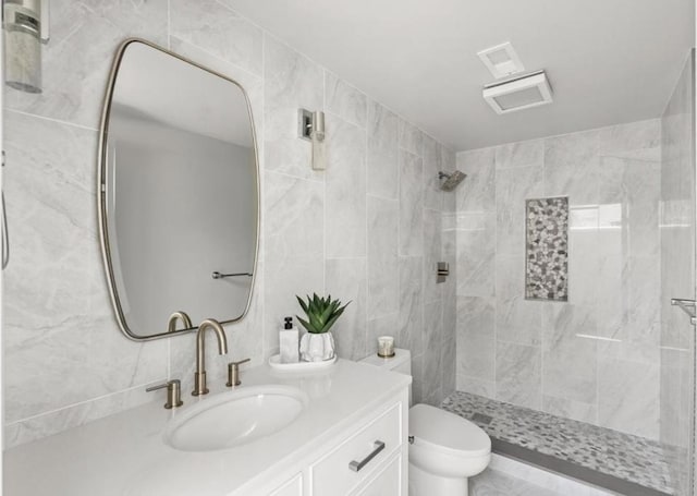 bathroom featuring vanity, toilet, tile walls, and a tile shower