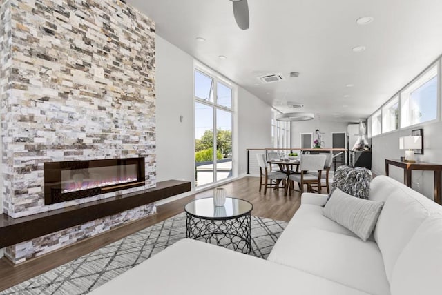 living room featuring hardwood / wood-style flooring, a large fireplace, plenty of natural light, and ceiling fan