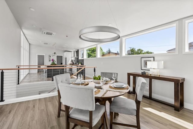 dining room with vaulted ceiling and light wood-type flooring