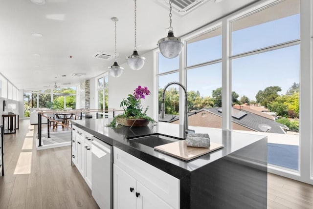 kitchen with white cabinetry, sink, stainless steel dishwasher, and an island with sink