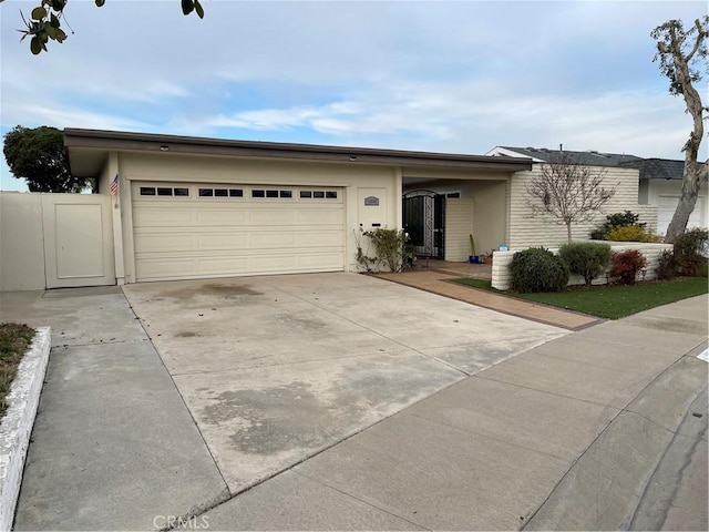 single story home with stucco siding, concrete driveway, an attached garage, and a gate