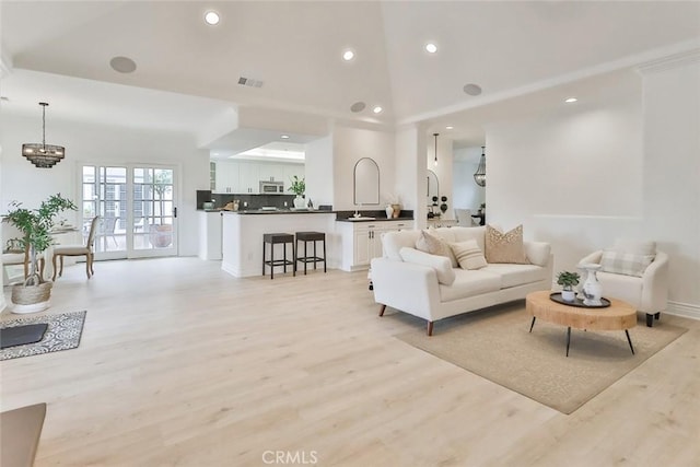 living room featuring a notable chandelier, light hardwood / wood-style floors, and a high ceiling