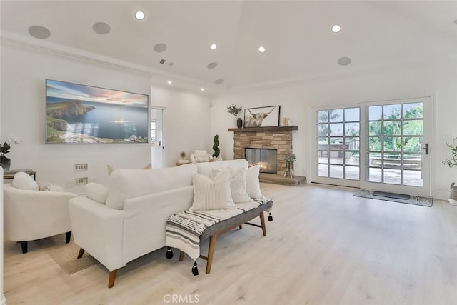 living room with ornamental molding, a stone fireplace, and light hardwood / wood-style flooring