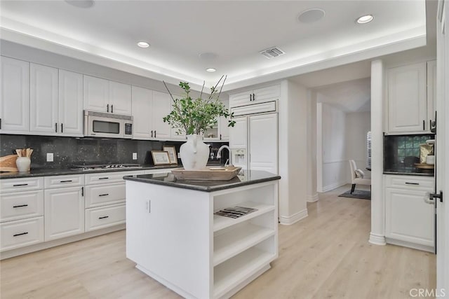 kitchen featuring light wood-type flooring, gas cooktop, a kitchen island with sink, and white cabinets