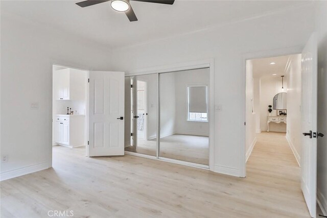 unfurnished bedroom featuring ceiling fan, a closet, and light wood-type flooring