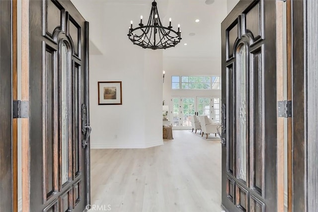 entrance foyer with a towering ceiling, light hardwood / wood-style flooring, and a notable chandelier