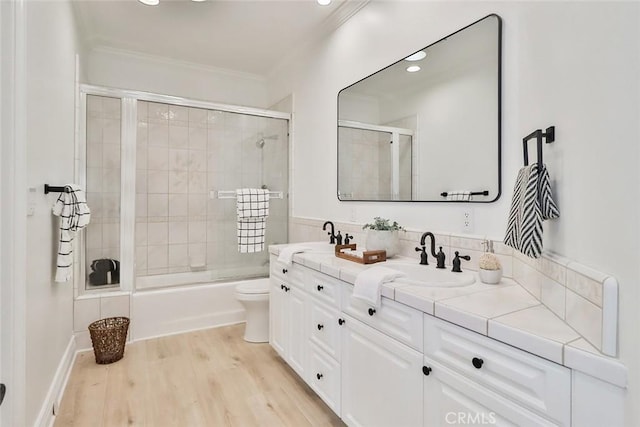 full bathroom featuring toilet, combined bath / shower with glass door, ornamental molding, vanity, and hardwood / wood-style floors