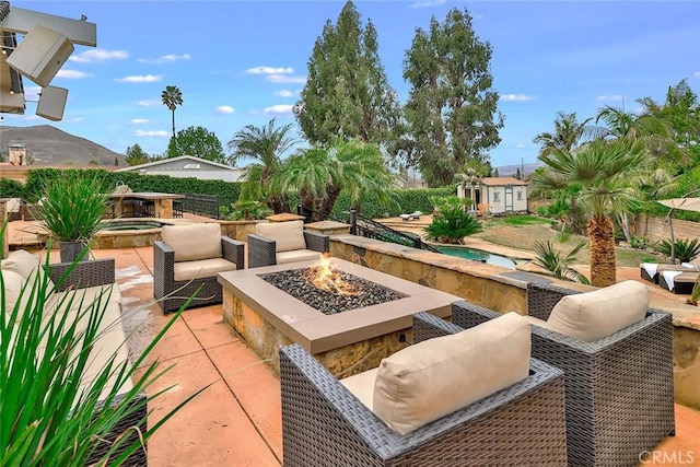 view of patio with an in ground hot tub, a storage unit, a mountain view, and a fire pit