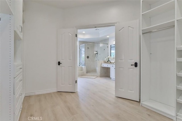 walk in closet with light hardwood / wood-style floors