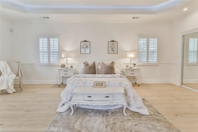 bedroom featuring light wood-type flooring and a tray ceiling