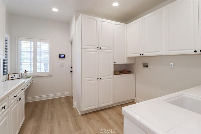 clothes washing area featuring cabinets, washer hookup, and light wood-type flooring