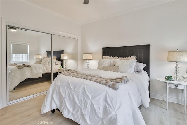 bedroom with light hardwood / wood-style flooring, ornamental molding, a closet, and ceiling fan