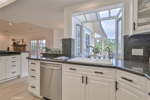 kitchen with sink, backsplash, light hardwood / wood-style floors, white cabinets, and stainless steel dishwasher