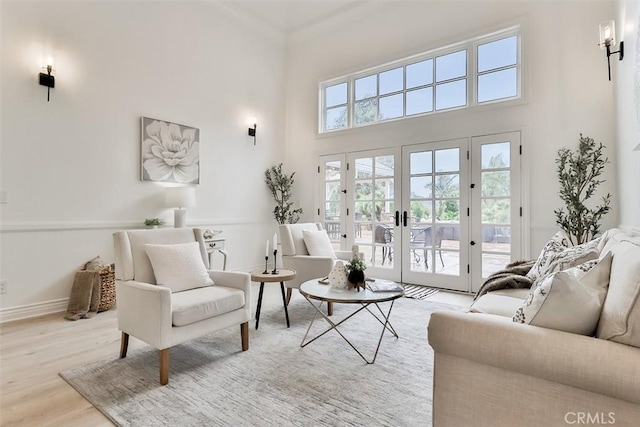 living room with french doors, a high ceiling, and light wood-type flooring