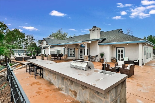 rear view of property featuring area for grilling, an outdoor hangout area, a patio area, and a wet bar