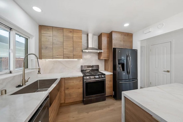 kitchen featuring refrigerator with ice dispenser, sink, tasteful backsplash, gas stove, and wall chimney exhaust hood