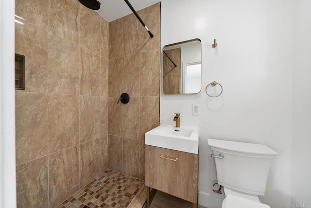 bathroom featuring vanity, a tile shower, and toilet