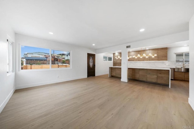 unfurnished living room featuring sink and light hardwood / wood-style floors