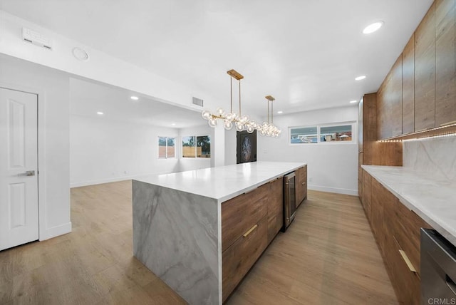 kitchen featuring an inviting chandelier, decorative light fixtures, light hardwood / wood-style flooring, a kitchen island, and beverage cooler