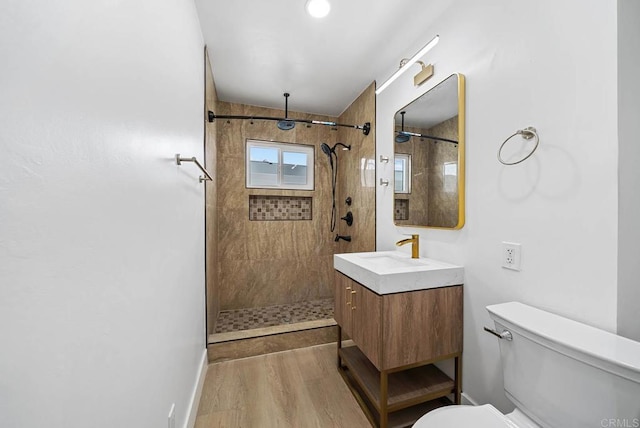 bathroom featuring vanity, wood-type flooring, toilet, and tiled shower