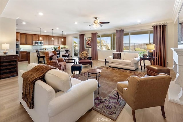 living room featuring light wood-style floors, baseboards, crown molding, and recessed lighting