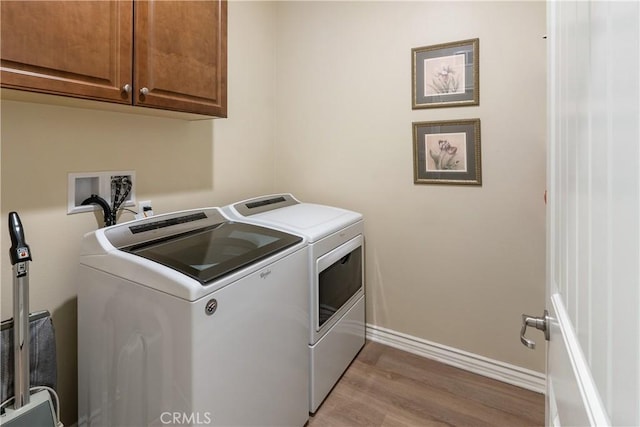 washroom with light wood-style floors, cabinet space, independent washer and dryer, and baseboards