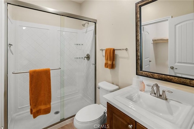 bathroom with a stall shower, vanity, and toilet