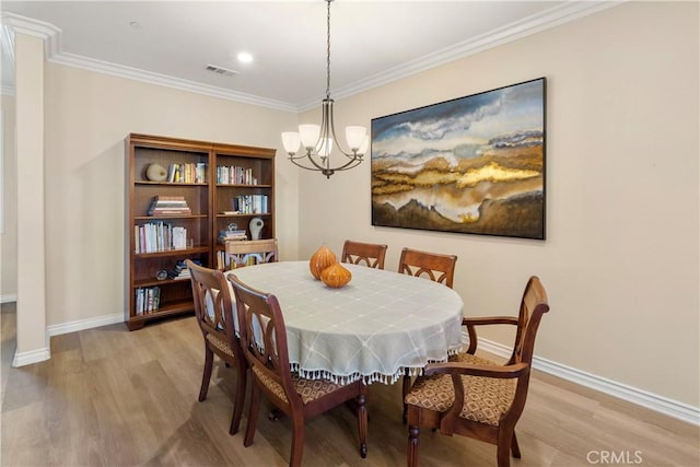 dining room featuring light wood-type flooring, an inviting chandelier, baseboards, and crown molding