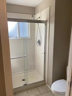 bathroom with tile patterned flooring, an enclosed shower, and toilet