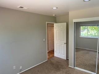 unfurnished bedroom with a closet and dark colored carpet