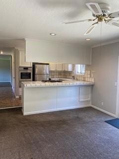 kitchen featuring dark colored carpet, stainless steel appliances, kitchen peninsula, and white cabinets