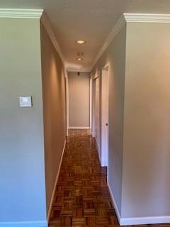 corridor with dark parquet flooring and ornamental molding