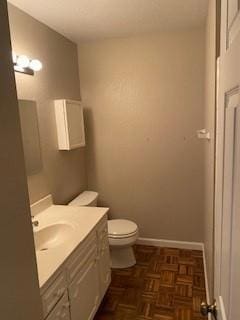 bathroom featuring vanity, parquet flooring, and toilet