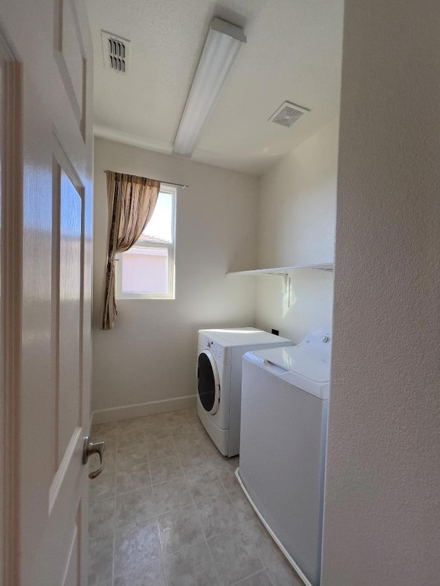 laundry area with washing machine and dryer and light tile patterned floors