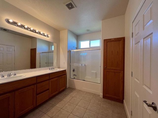 bathroom featuring vanity, combined bath / shower with glass door, tile patterned floors, and a textured ceiling