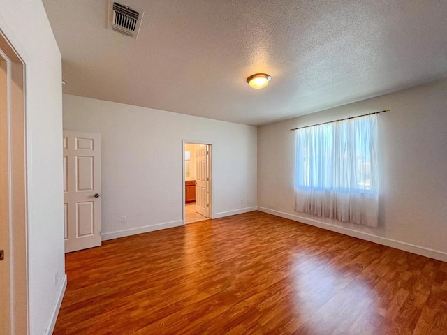 unfurnished room with wood-type flooring and a textured ceiling